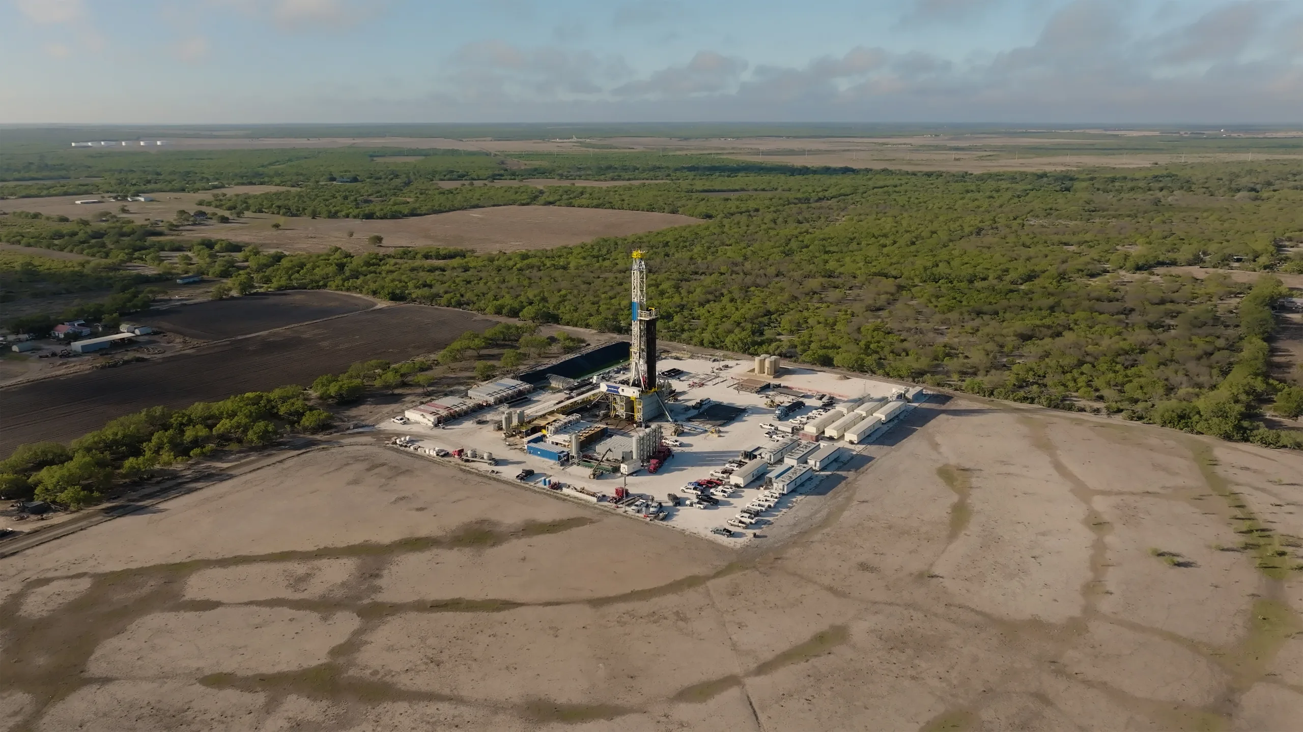 Aerial view of a drilling site surrounded by fields and woodland